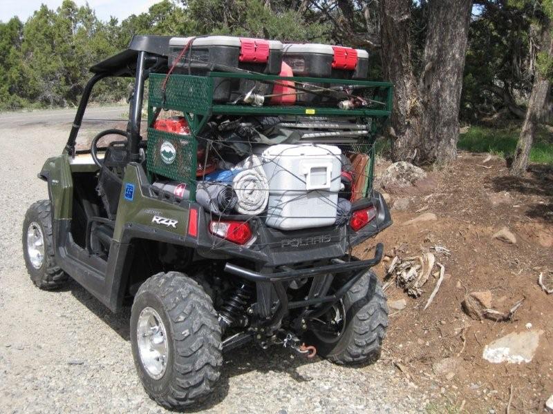 UTV in a forest road with a rack filled with coolers